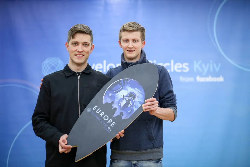 Two individuals presenting an award from a competition.